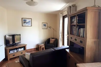 a living room with a couch and a television at The Snug a cosy, quirky detached cottage with sea views in Innellan