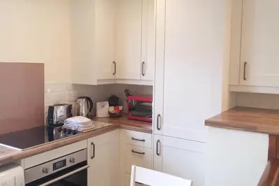 a kitchen with white cabinets and a counter top at The Snug a cosy, quirky detached cottage with sea views in Innellan