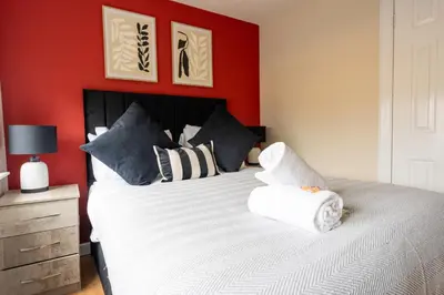 a bedroom with a large bed with a red wall at Beauly Court Suites in Grangemouth