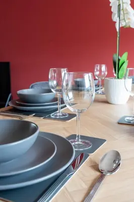 a wooden table with plates and wine glasses on it at Beauly Court Suites in Grangemouth