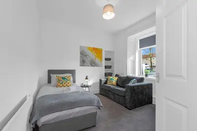 a bedroom with a bed and a couch at Arran Cottage - 4 Bed Home on M8 in Coatbridge