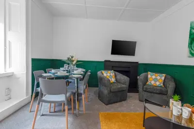 a dining room with a table and chairs and a television at Arran Cottage - 4 Bed Home on M8 in Coatbridge