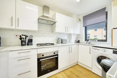 a kitchen with white cabinets and a washer and dryer at 2BR Flat with Free Parking in Central Location in Glasgow