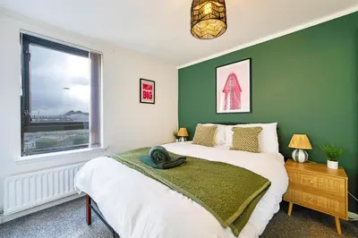 a green bedroom with a bed and a window at 2BR Flat with Free Parking in Central Location in Glasgow