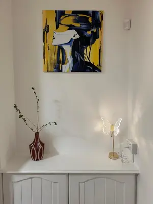 a white cabinet with a vase and a painting on the wall at Private main door Two Bedrooms Apartment in Edinburgh