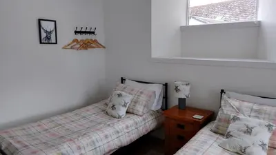 a bedroom with two twin beds and a window at Coach House Cottage a cosy, detached hideaway with garden, nr the sea in Innellan