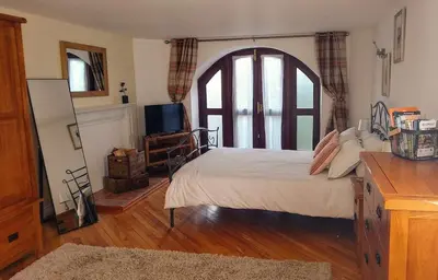 a bedroom with a bed and a tv in it at Coach House Cottage a cosy, detached hideaway with garden, nr the sea in Innellan