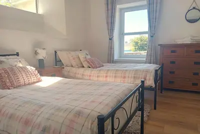 a bedroom with two beds and a dresser and a window at Coach House Cottage a cosy, detached hideaway with garden, nr the sea in Innellan