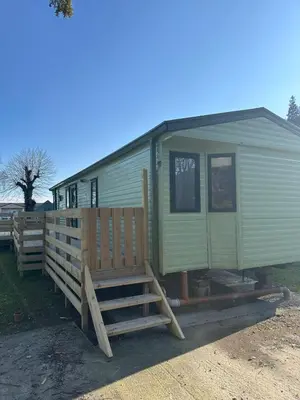 a green mobile home with a wooden fence at Aspen Scenic 53 in Ardentinny