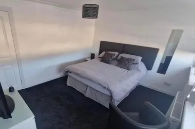 a bedroom with a bed with pillows and a chair at Cozy Shotts House with 2 Bedrooms in Kirk of Shotts
