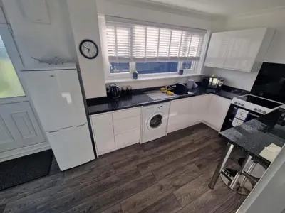 a kitchen with white cabinets and a sink and a dishwasher at Cozy Shotts House with 2 Bedrooms in Kirk of Shotts