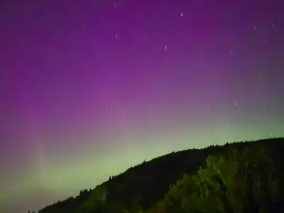 a green and purple sky over a hill with trees at Holy Loch View in Strone