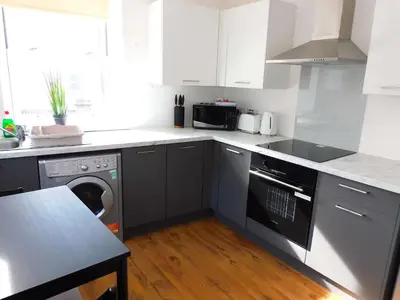 a kitchen with white cabinets and a dishwasher at No 3 - Modern Studio Apartment in Lanark Town Centre in Lanark