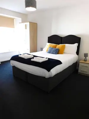 a bedroom with a large bed with yellow and blue pillows at No 5 - Modern 2 bedroom Apartment in Lanark Town Centre in Lanark