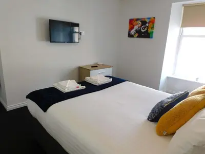 a bedroom with a large white bed with a tv on the wall at No 5 - Modern 2 bedroom Apartment in Lanark Town Centre in Lanark