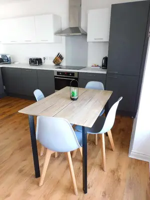 a wooden table in a kitchen with white chairs at No 5 - Modern 2 bedroom Apartment in Lanark Town Centre in Lanark