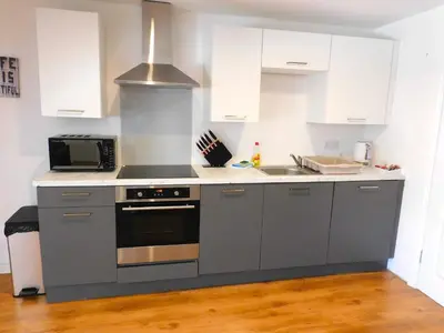 a kitchen with white cabinets and a stove top oven at No 7 - Modern 1 Bedroom Apartment in Lanark Town Centre in Lanark