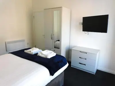 a bedroom with a bed with a dresser and a tv at No 9 - Modern 3 Bedroom Apartment in Lanark Town Centre in Lanark