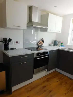 a kitchen with white cabinets and a black stove top oven at No 11 - Contemporary 2 Bedroom Apartment in Lanark Town Centre in Lanark