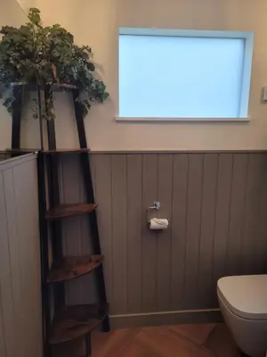 a bathroom with a shelf with two potted plants at Hot Tub Cottage in Ayrshire in Stewarton