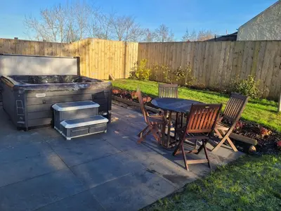 a backyard with a grill and a table and chairs at Hot Tub Cottage in Ayrshire in Stewarton