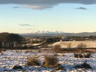 a snow covered field with mountains in the background at Stunning Barn Conversion in Dunlop