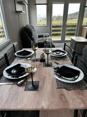 a wooden table with wine glasses and plates on it at Swift Bordeaux Sea View 10 in Ardentinny