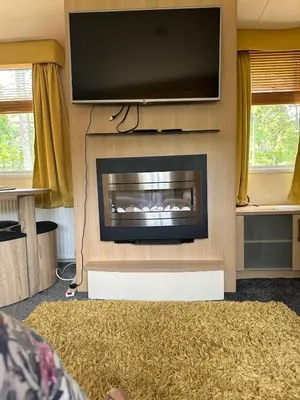 a living room with a fireplace with a flat screen tv at Swift Serenity 50 in Ardentinny