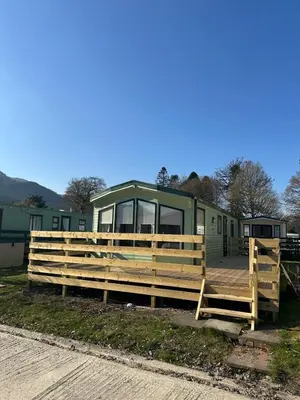 a green trailer with a deck and a house at Winchester 23 in Ardentinny