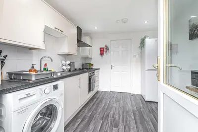 a white kitchen with a washer and dryer at Pure Home Oakley Park View by TBA in Dunfermline
