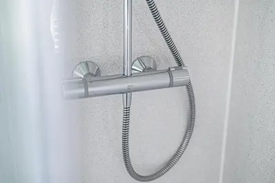 a shower head with a hose attached to a shower curtain at Pure Home Oakley Park View by TBA in Dunfermline