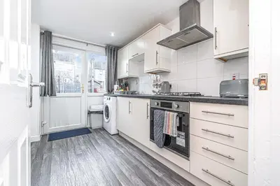 a kitchen with white cabinets and a stove top oven at Pure Home Oakley Park View by TBA in Dunfermline