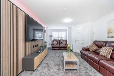 a living room with a leather couch and a tv at Super Prime Luxury 4 Bedroom Detached Home by TBA in Fife