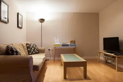 a living room with a couch and a tv at Bright & Stylish West End Apartment in Edinburgh