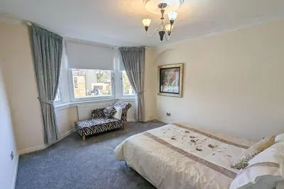 a bedroom with a bed and a chair and a window at The Old High Road, North Ayrshire in Stevenston