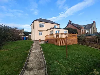 a house with an orange fence in the yard at The Old High Road, North Ayrshire in Stevenston