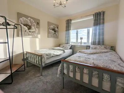 a bedroom with two beds and a window at The Old High Road, North Ayrshire in Stevenston