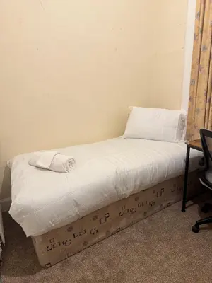 a bed with white sheets and a pillow on it at Haymarket Centro , Flat familiar quarto privativo banheiro compartilhado in Edinburgh