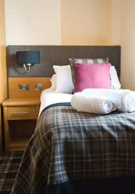a bedroom with a bed with pillows and a night stand at The Cornhill Inn in Falkirk