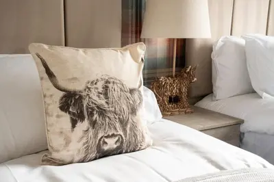 a pillow with a cow on it sitting on a couch at The Rise Retreat in Livingston