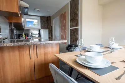 a kitchen with a wooden table with plates and wine glasses at Marina House in Bathgate