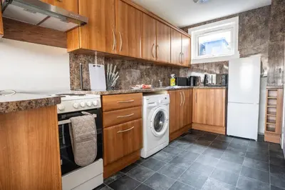 a kitchen with wooden cabinets and a washer and dryer at Marina House in Bathgate