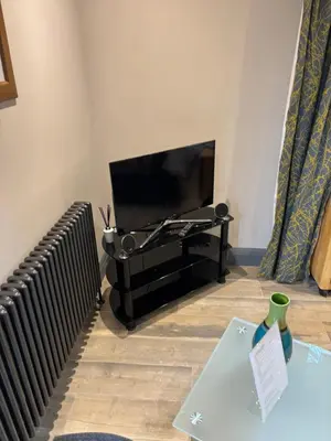a living room with a television and a table with a vase at The Snook-Free Parking-Near Pentland Hills in Loanhead