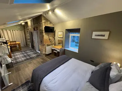 a bedroom with a bed and a room with a window at Crannaig House in Aberfoyle