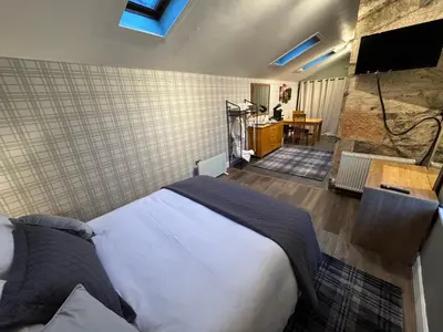 a bedroom with a large bed and a bathroom at Crannaig House in Aberfoyle