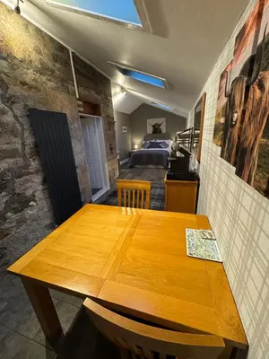 a wooden table in a room with a bedroom at Crannaig House in Aberfoyle