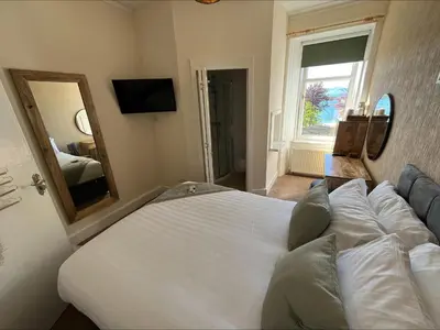a bedroom with a large white bed and a mirror at Glenroy Guest House in Oban