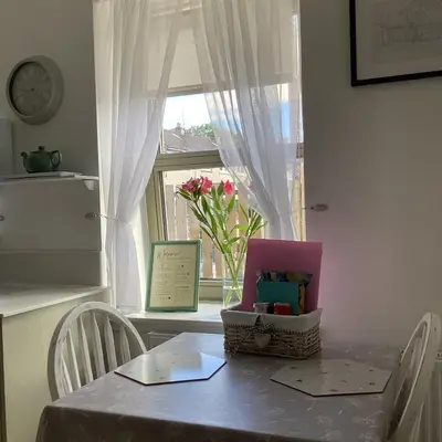 a table with a vase of flowers and a window at Cottage in Mid Calder Village near Edinburgh in Mid Calder