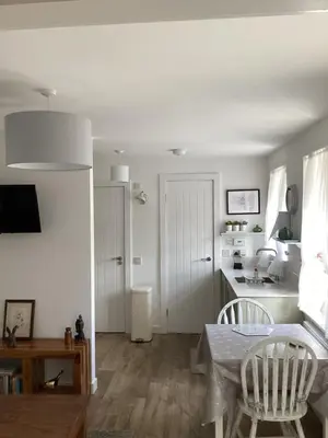 a living room with a table and a kitchen at Cottage in Mid Calder Village near Edinburgh in Mid Calder