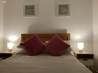 two purple pillows sitting on a bed with two lamps at Cottage in Mid Calder Village near Edinburgh in Mid Calder